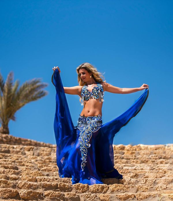Woman in a flowing movement pose against a cream background.
